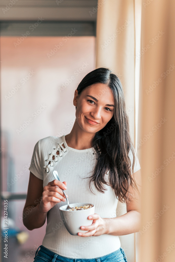 一位微笑的年轻女性吃着健康早餐的肖像。