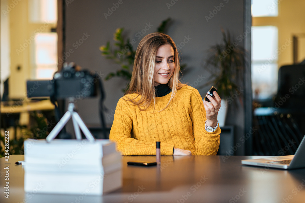 一位年轻女士正在录制关于新化妆品的视频博客。