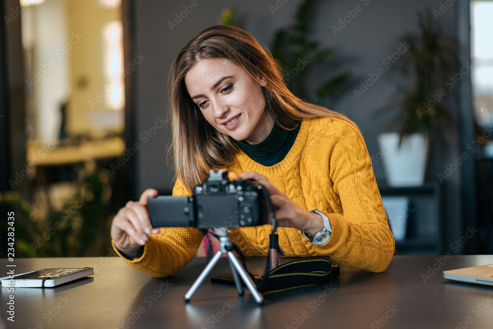 Young woman preparing camera for vlogging.