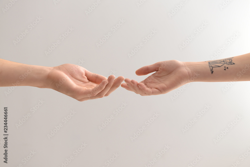 Male and female hands reaching out to each other on light background