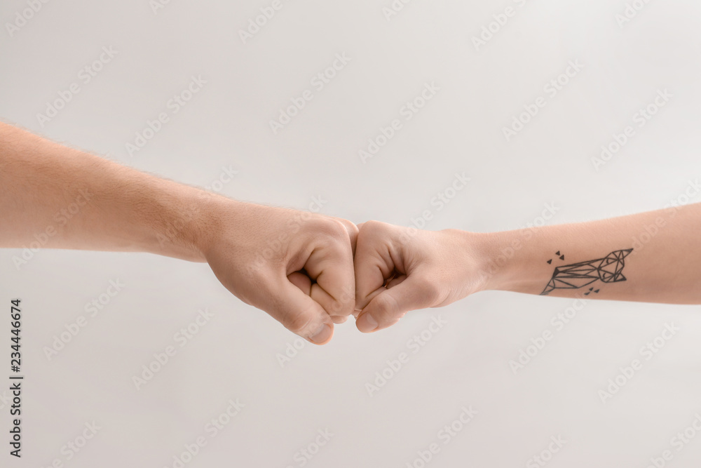 Man and woman making fist bump gesture on light background