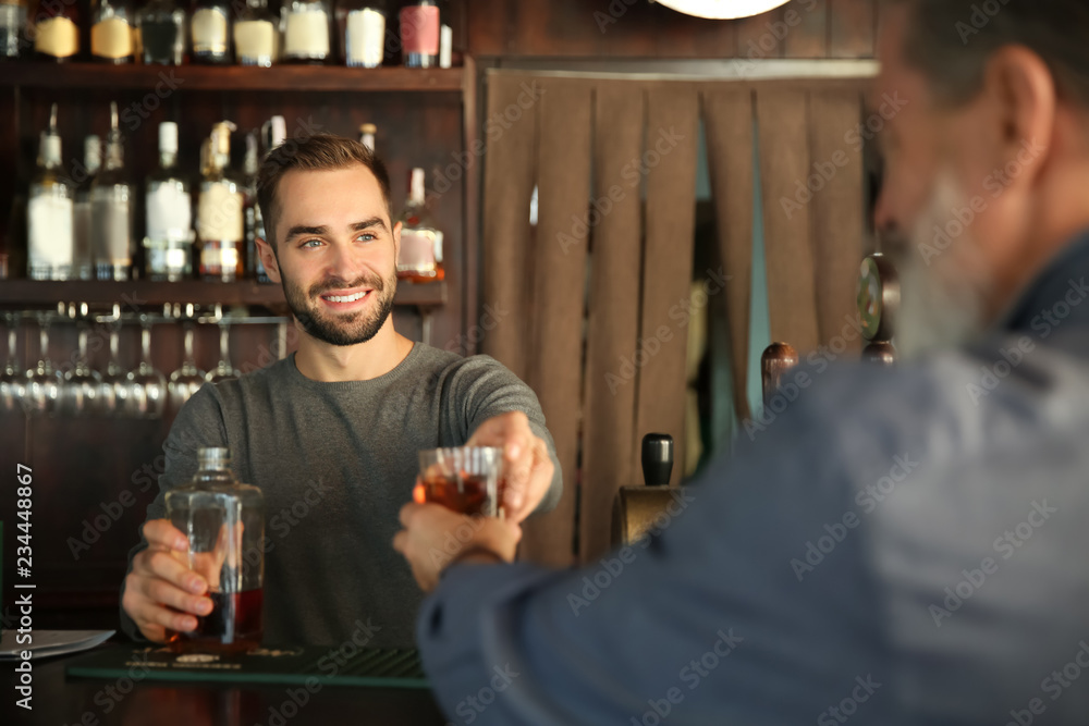 年轻酒吧男招待在酒吧为客户服务