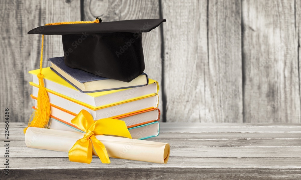 Graduation mortarboard on top of stack of books on  background