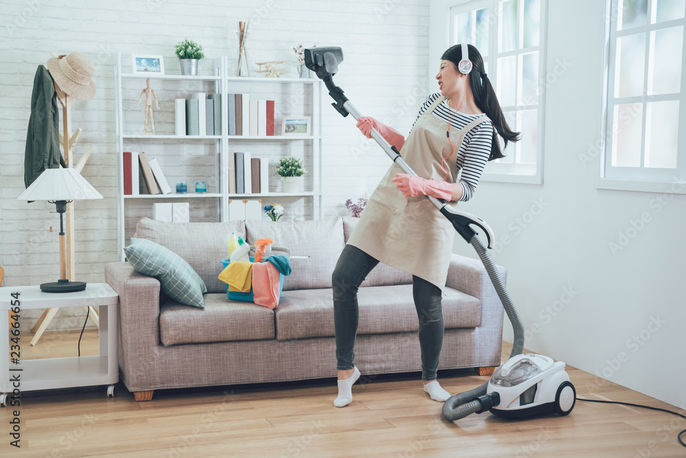 asian wife cleaning home playing vacuum cleaner.