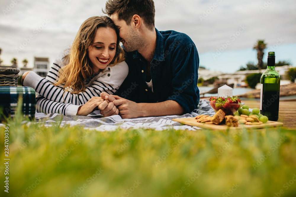 Romantic couple out on picnic lying on the ground