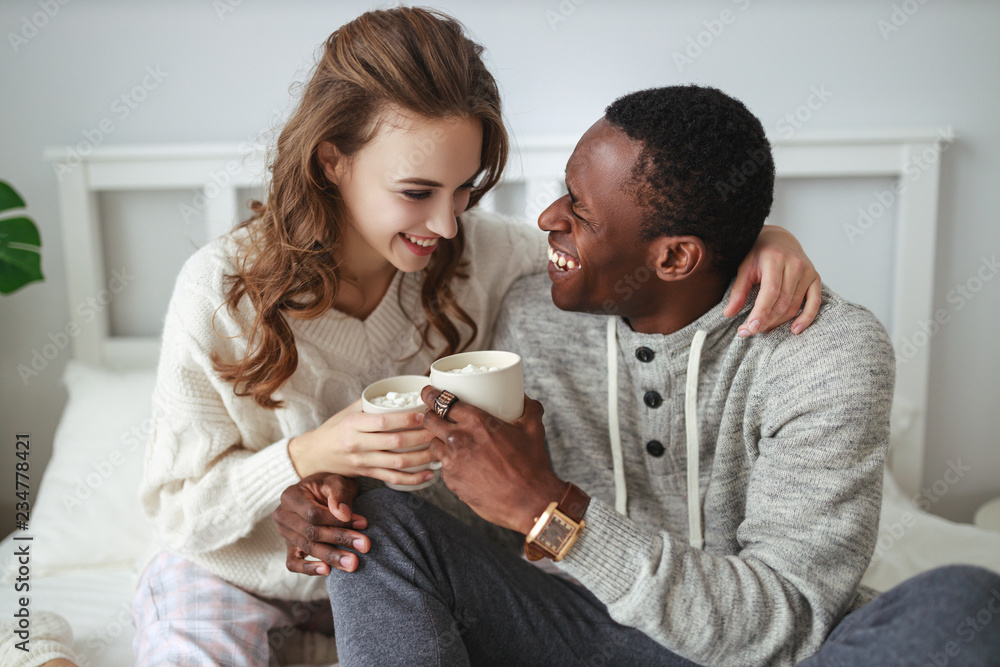 happy loving couple drinking cocoa on winter morning in bed