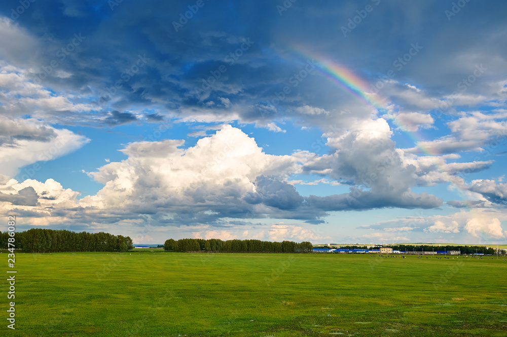 The beautiful cloudscape and rainbow on the grassland.