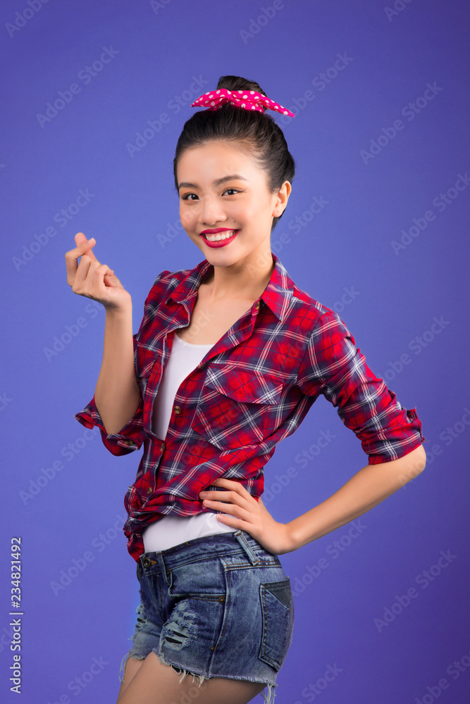 Smiling lovely asian woman dressed in pin-up style dress over blue.