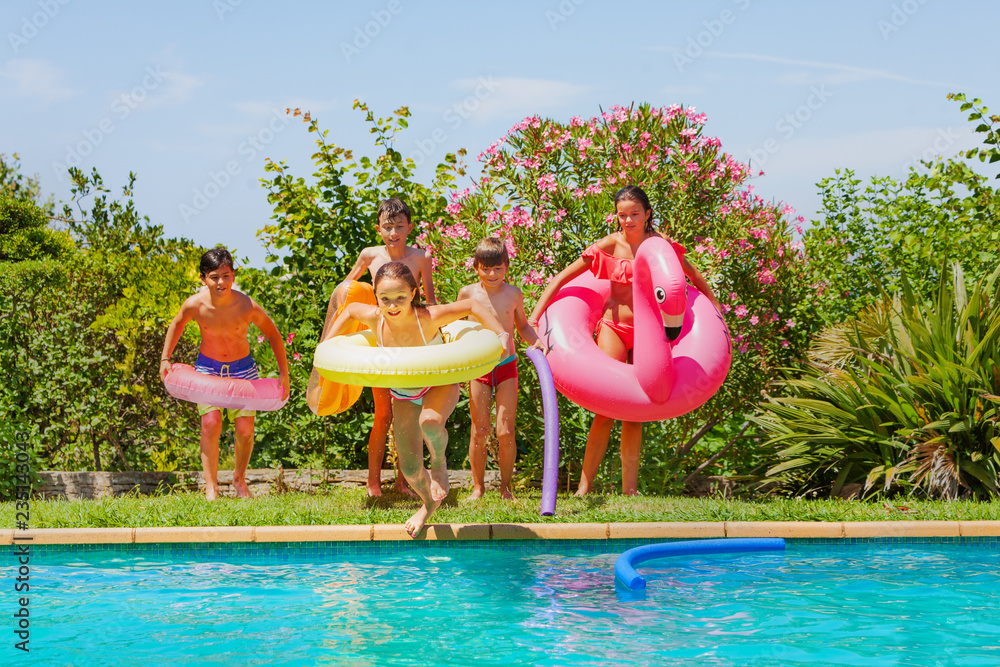 Cute girl jumping in swimming pool with friends