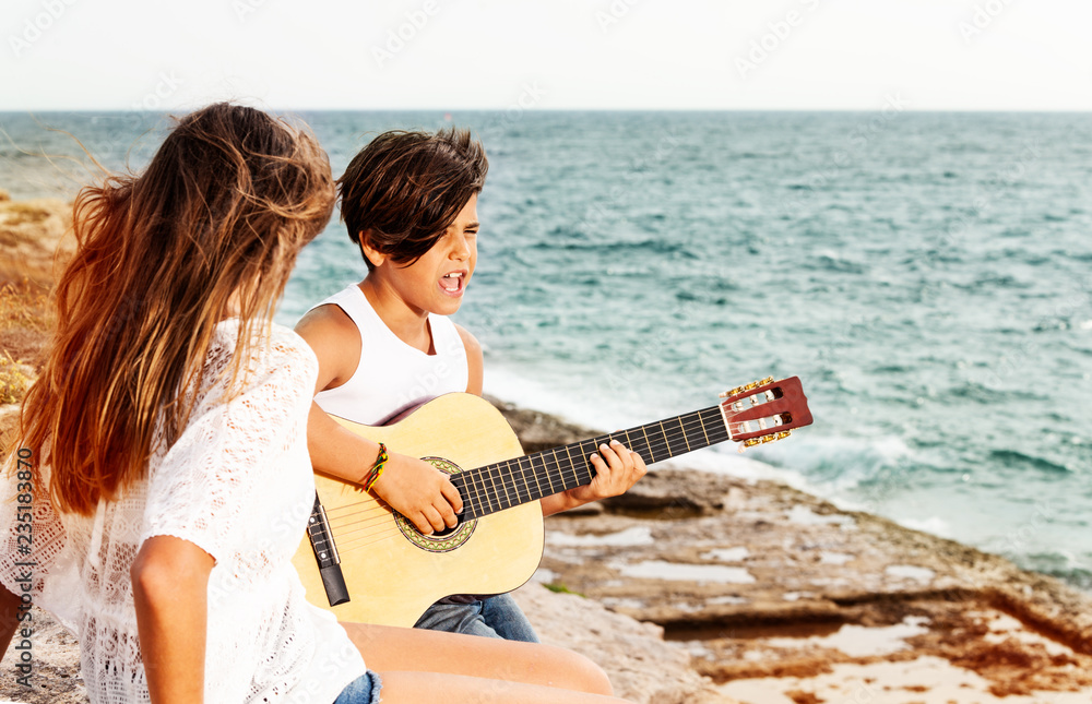 Boy playing guitar and singing for girl outdoors