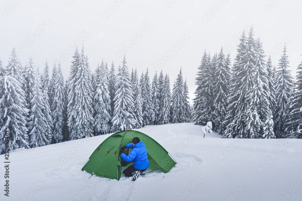 在白雪皑皑的松林背景下，绿色帐篷和游客。令人惊叹的冬季景观。Tou