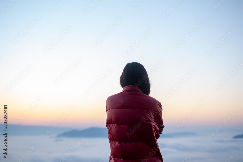 Woman standing on the mountain above foggy valley.Woman watch over misty and foggy morning valley to