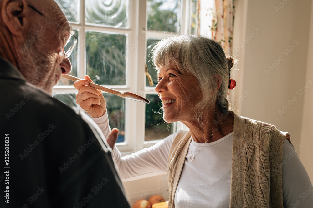 Woman tasting the food prepared by her husband