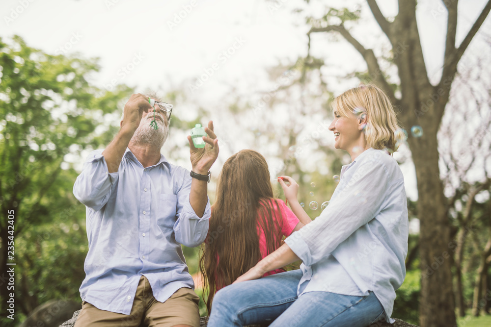 à¹‡Happy family blow soap bubbles in park.