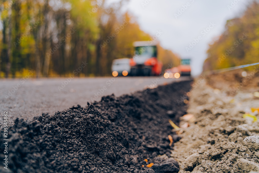 在道路上铺设新的沥青。工人在道路施工期间操作沥青摊铺机。C