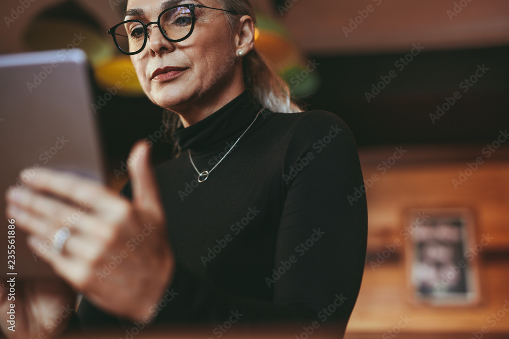 咖啡馆的老年女性使用数字平板电脑