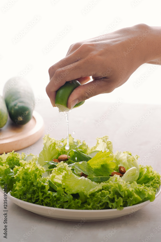 Green vegan breakfast meal in bowl with lettuce, cucumber, lime and almond. Girl holding plate with 