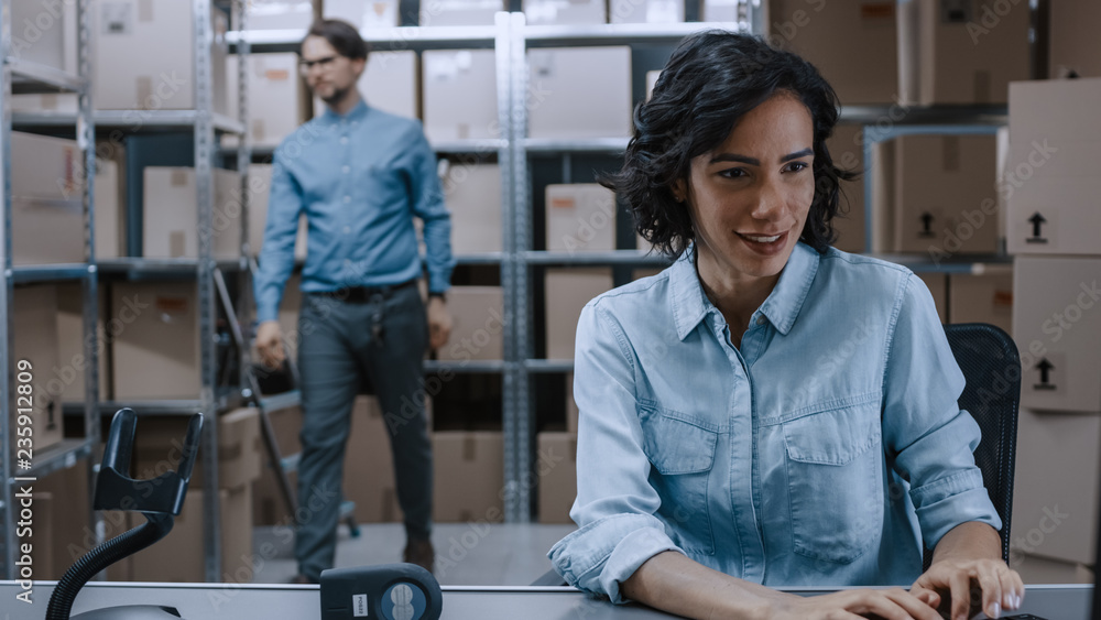 Female Inventory Manager Sitting at Her Desk and Using Personal Computer, Worker Puts Packages on th