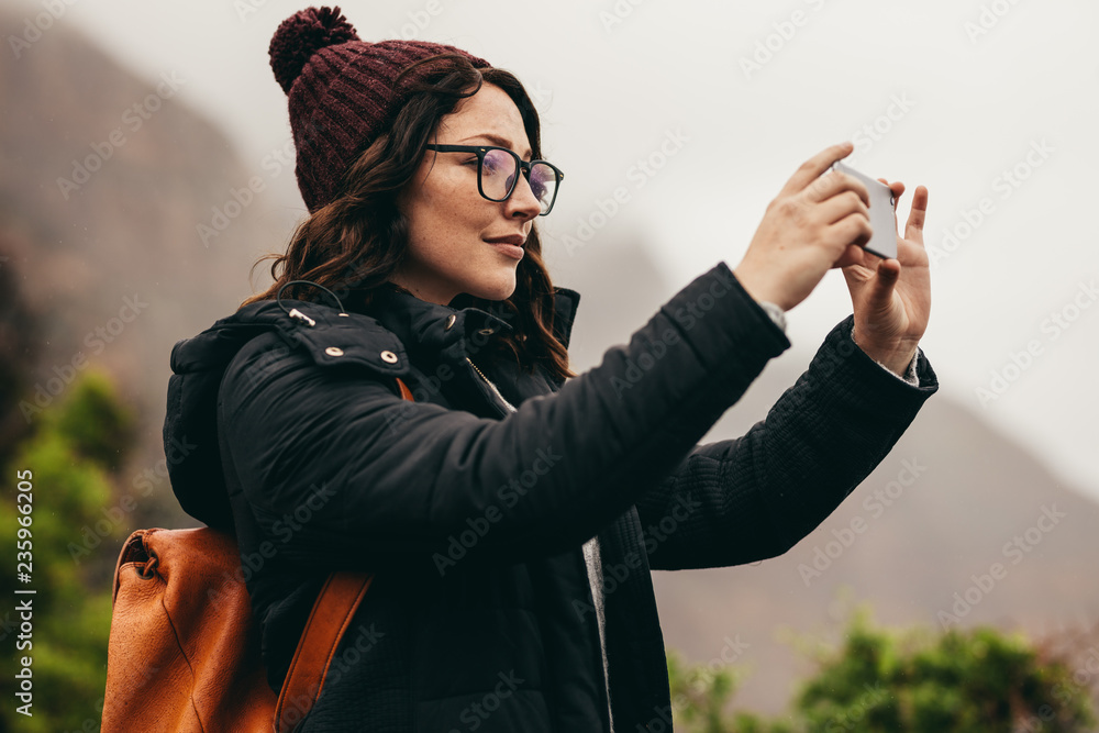 女游客用手机拍摄风景