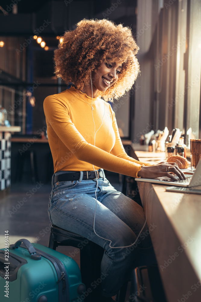 Female traveller working on laptop sitting at a restaurant