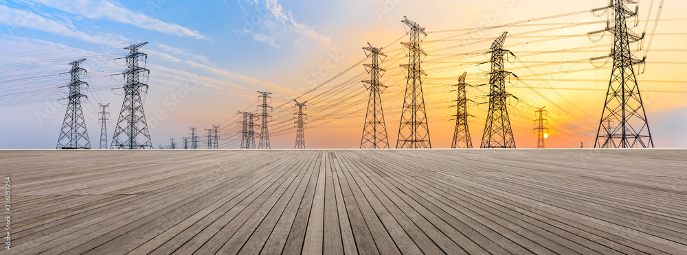 Wooden square floor and high voltage power towers at sunset