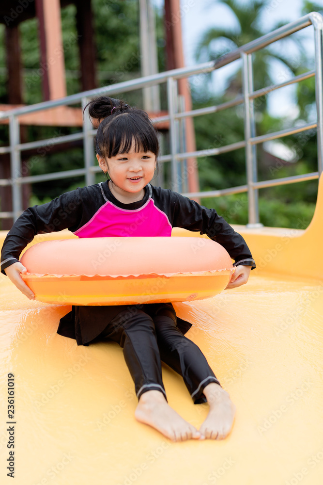 Asian girl with rubber ring in swimming pool