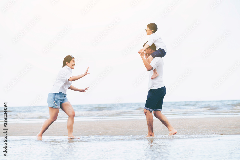 Happy family of father, mother and son goes vacation on a tropical sand beach in summer.