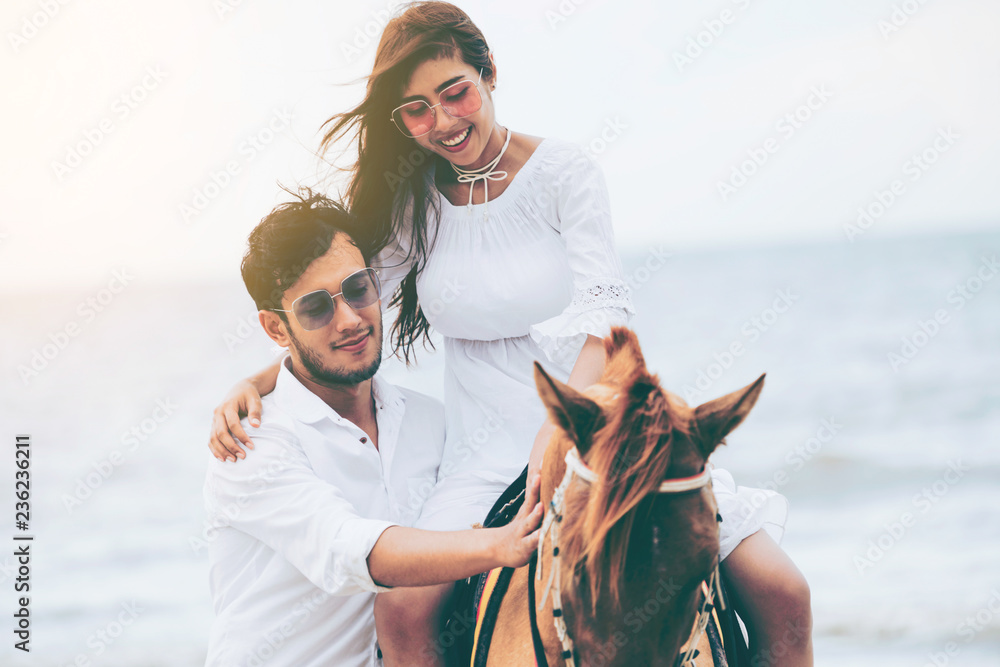 Young couple goes honeymoon horse riding on the beach in summer vacation.