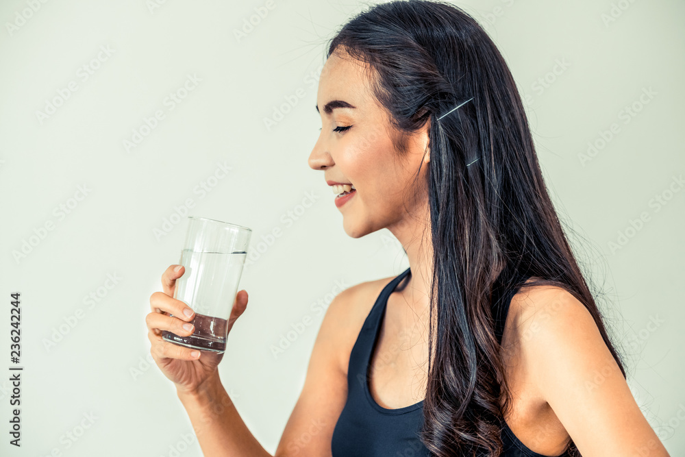 Woman in sportswear drinking water in a fitness gym. Healthy lifestyle and hydration concept.