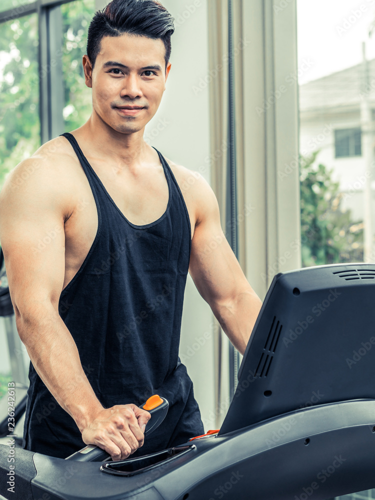 Sporty runner running on treadmill in fitness gym. Healthy lifestyle concept.