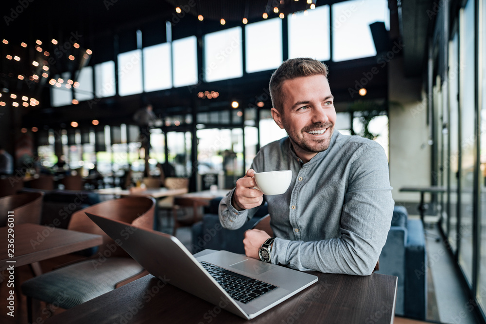 Handsome man drinking coffee in modern cafe.