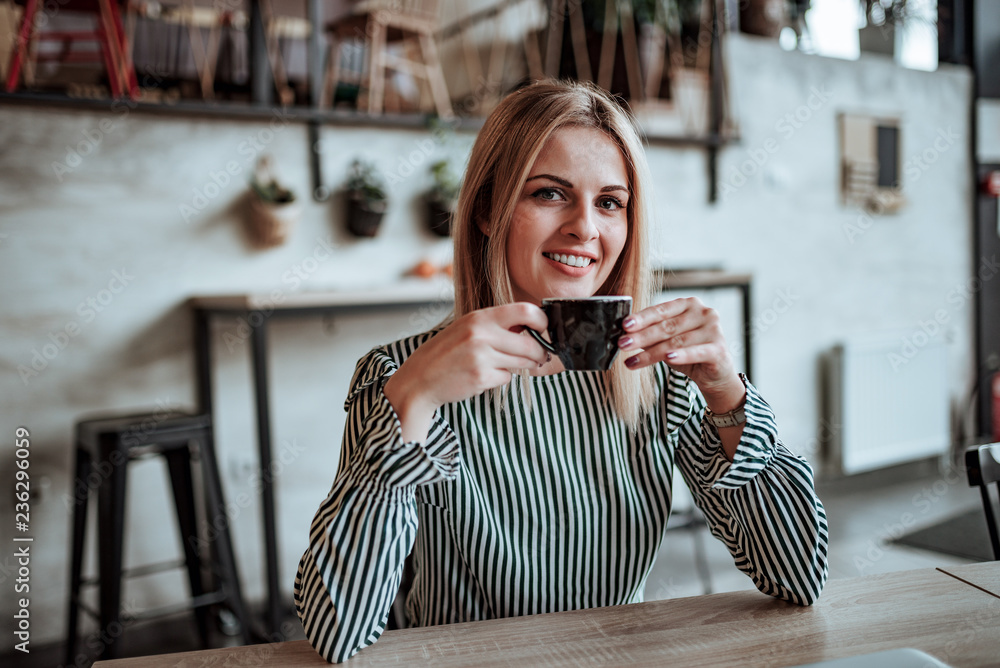 Portrait of a young woman holding coffee cup.