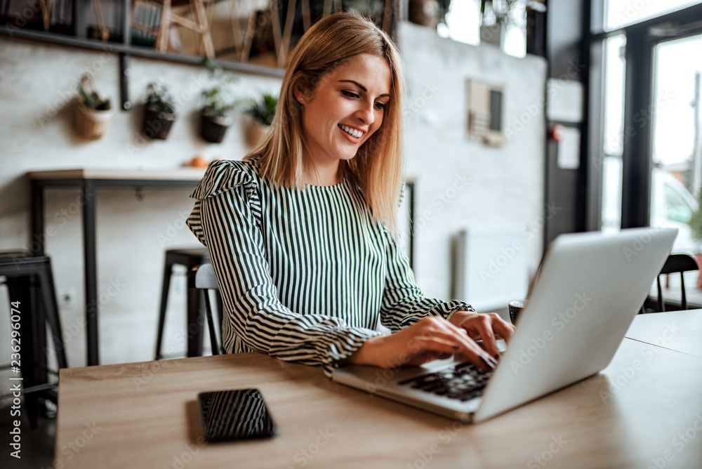 Smiling woman typing on laptop indoors.