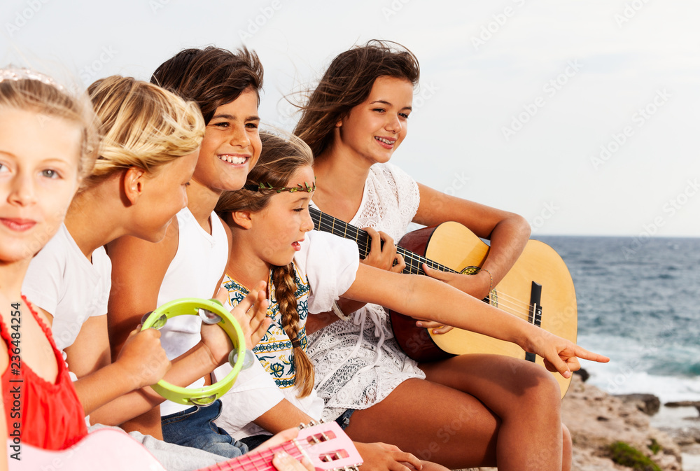 Young music band playing guitar at the seaside