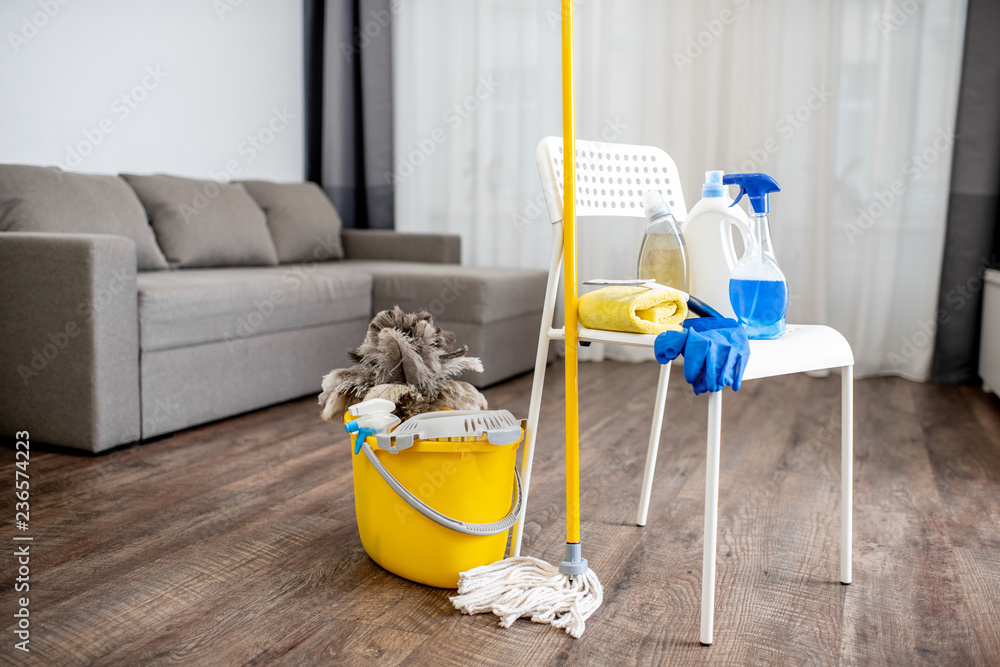 Bucket with dust wiper, sponges, chemicals bottles and mopping stick on the floor in the apartment. 