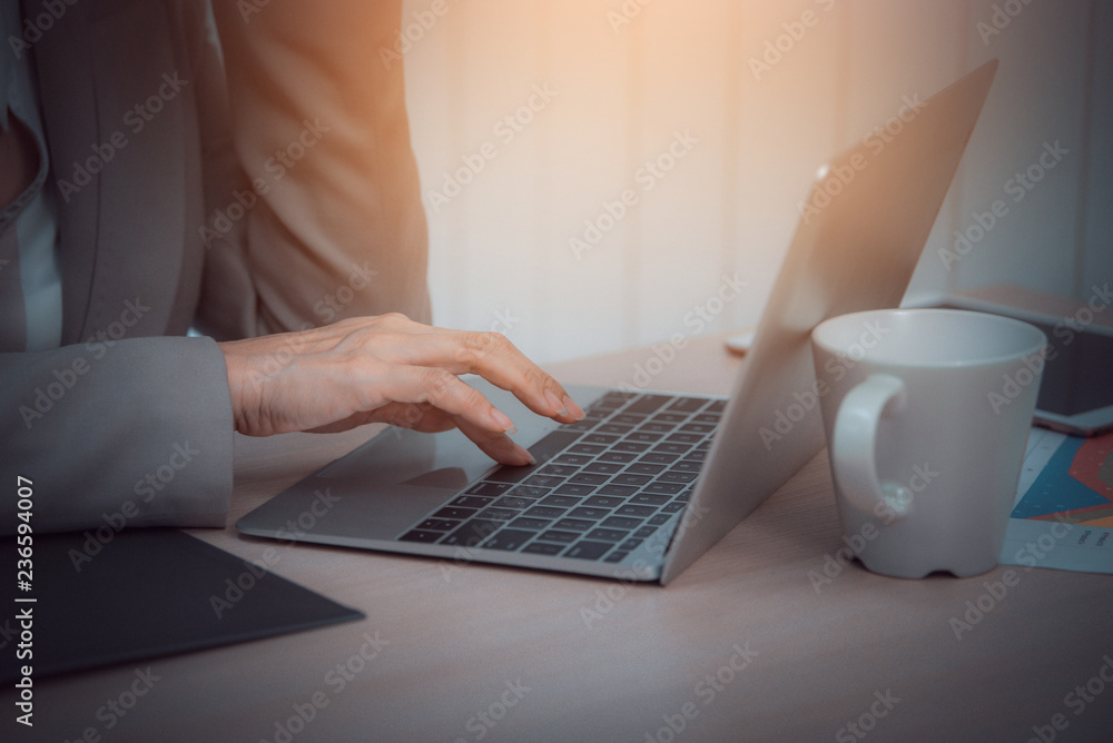 Business woman use laptop and white coffee cup in office. Vintage tone