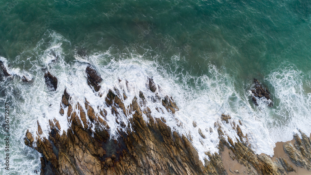 Aerial view drone shot of seascape scenic off beach in phuket thailand with wave crashing on the roc