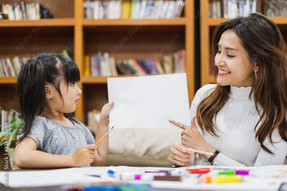 亚洲女孩和母亲在白纸上用彩色铅笔画画