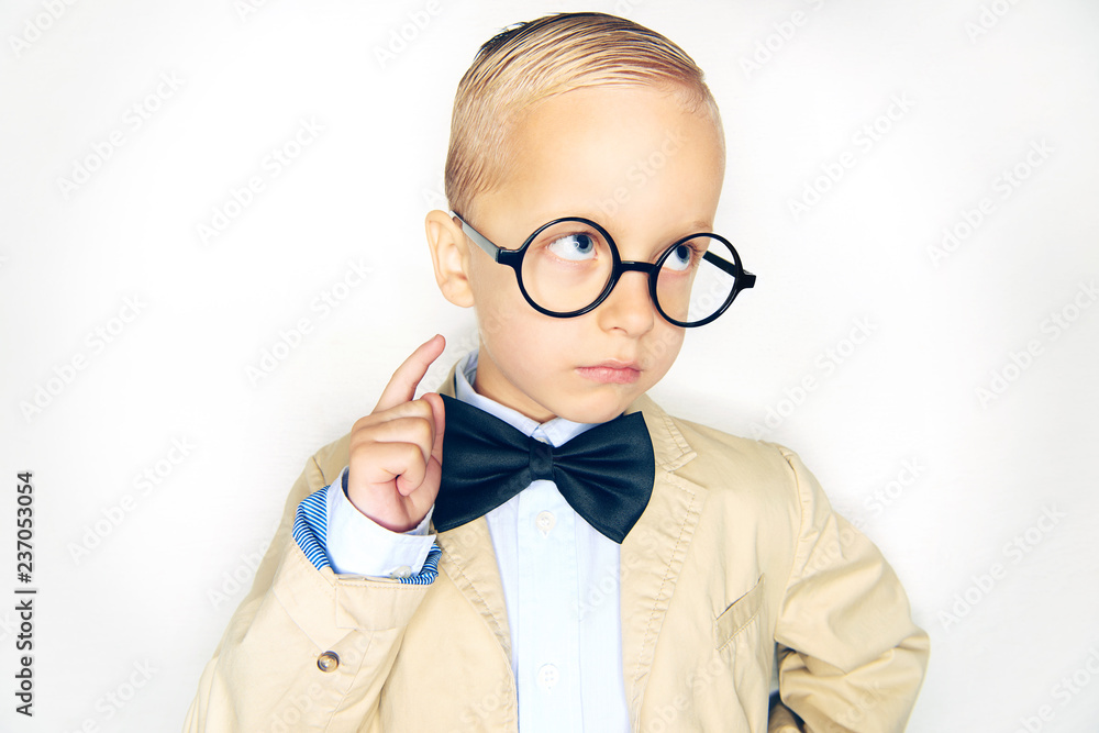 Little boy wearing glasses and a bowtie pointing upwards