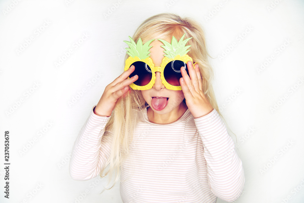 Cute little girl wearing pineapple glasses sticking out her tongue