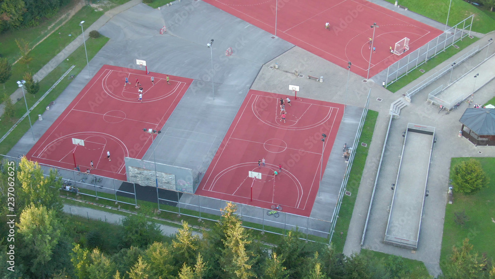 AERIAL: People playing sports on the new courts near middle class neighborhood.