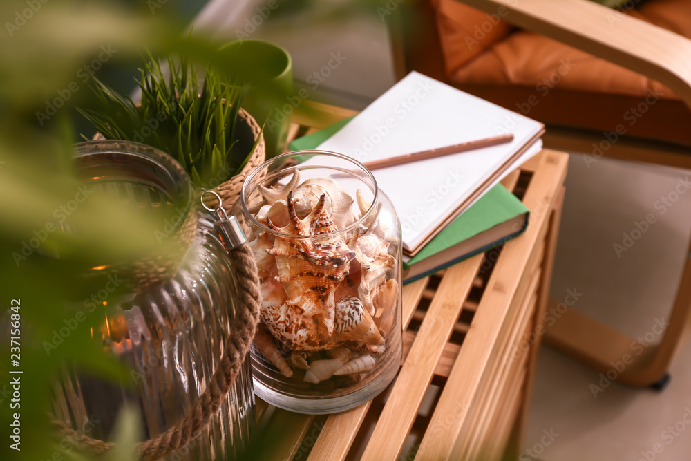 Glass jar with different sea shells on wooden table