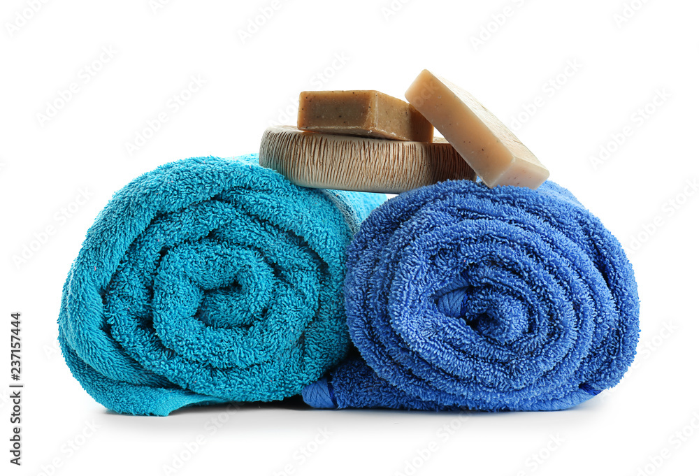 Rolled clean soft towels with soap bars on white background