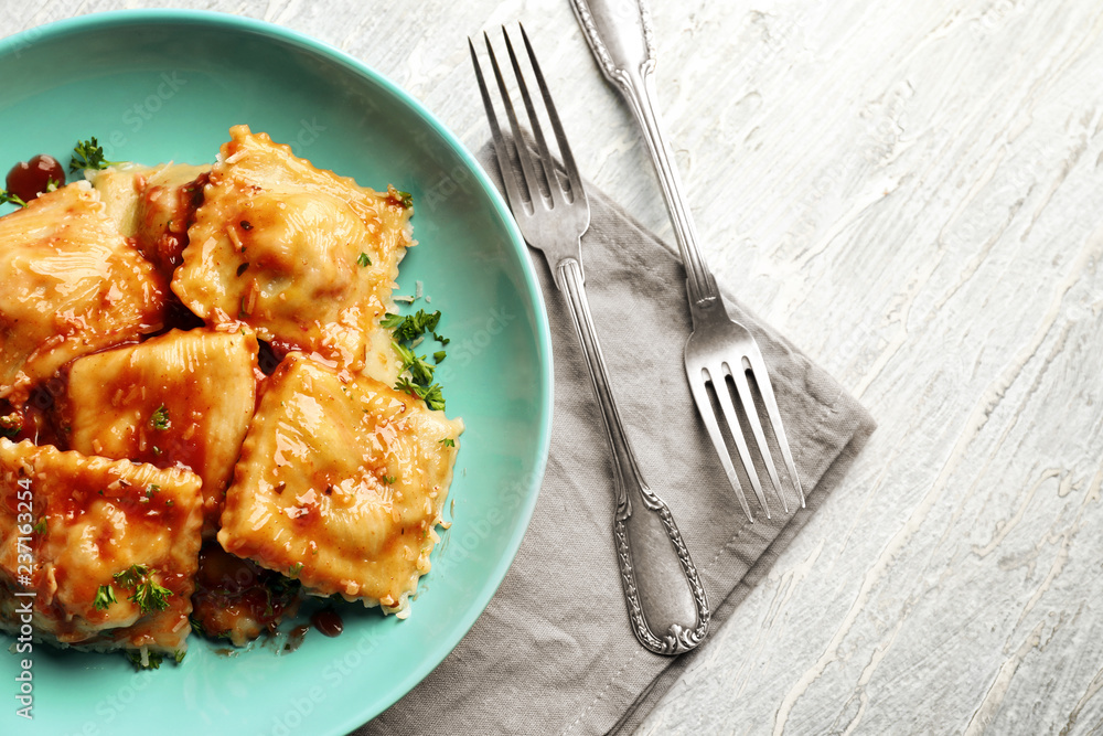 Plate with tasty ravioli on table, top view