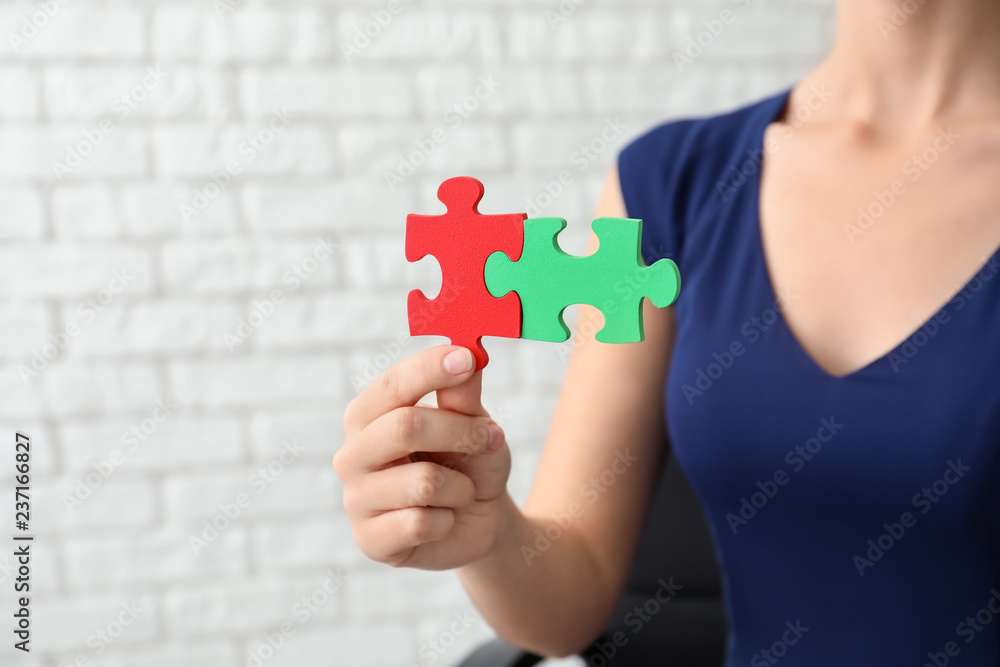 Woman with pieces of color puzzle on brick wall background