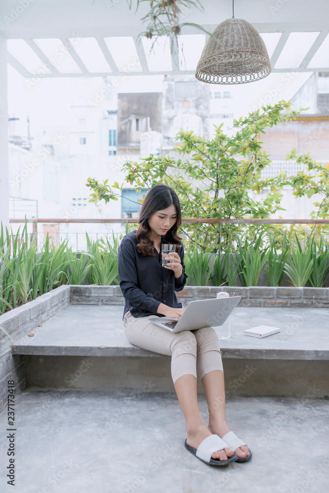 Enjoying nice time on fresh air. Beautiful young woman working on her laptop and smiling while sitti