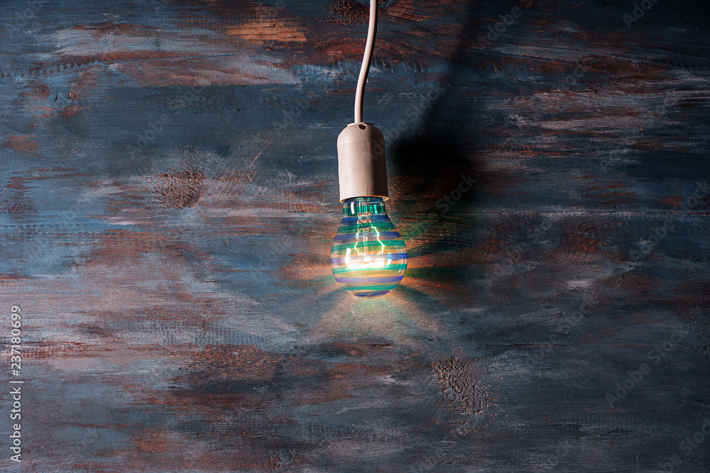 Glowing light bulb on color wooden background