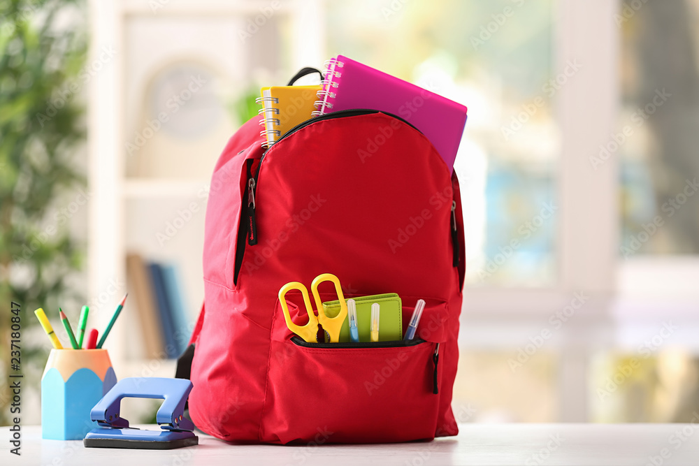 Backpack with school supplies on white table