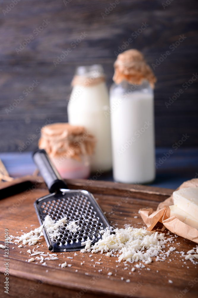 Cheese with grater on wooden board