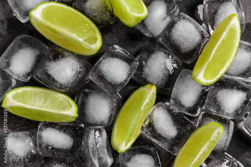 Fresh sliced ripe lime and ice cubes on grey background